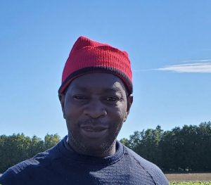 Smiling Jamaican man with blue sky and trees in the background