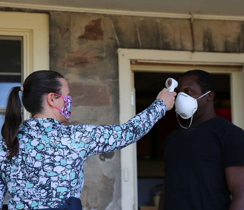 Jenn Pfenning measuring a team member's temperature before they start their work day.