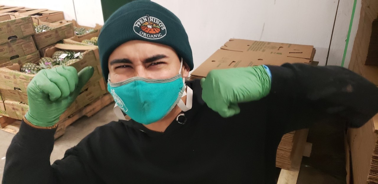 Warehouse worker, Josue, smiling wearing a mask, toque and gloves.
